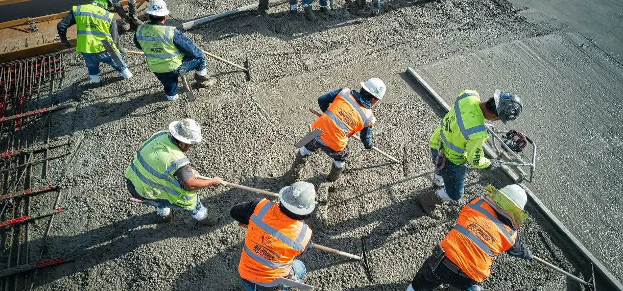 Construction workers leveling freshly poured concrete slab