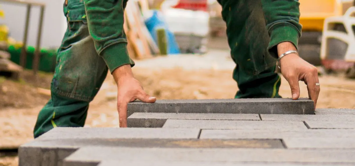 Worker placing concrete paving stones