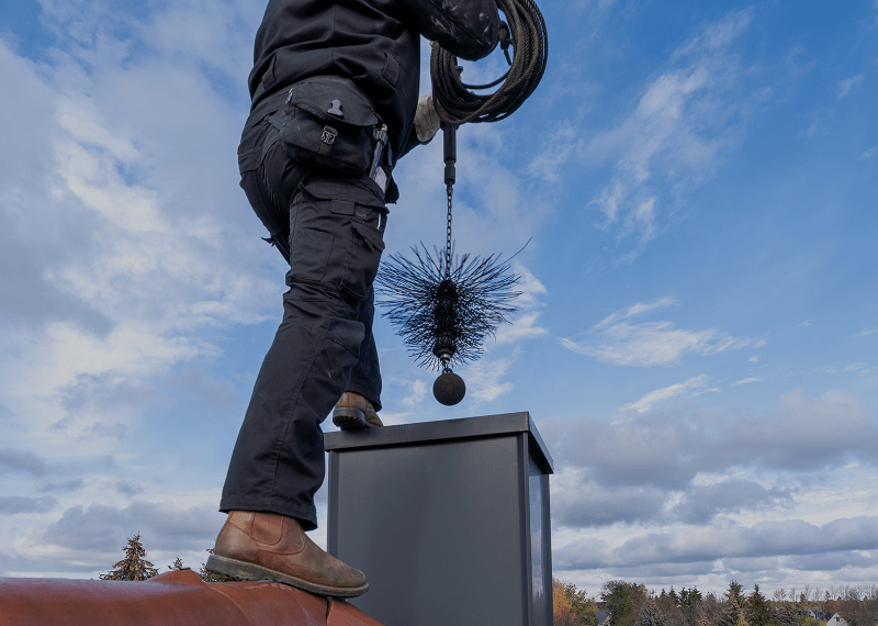 Worker cleaning chimney under clear sky